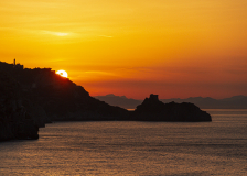 Sun rising among rocks of coastline